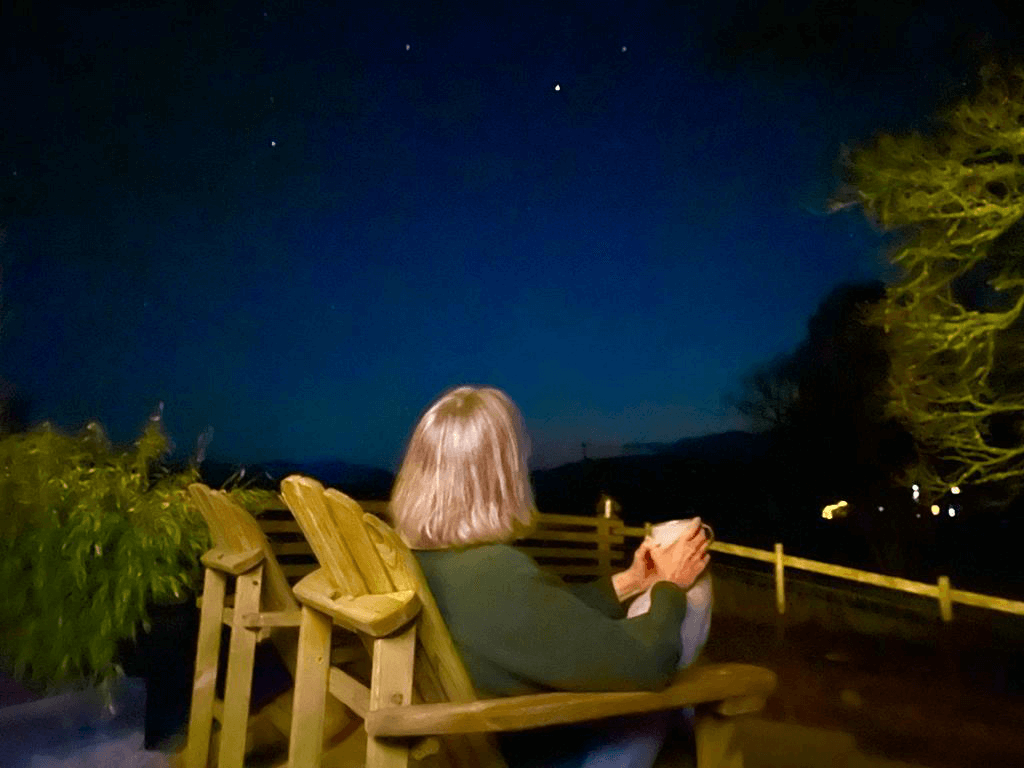 Person holding a cup of tea while starting up at the night sky